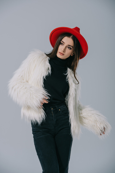 attractive elegant woman posing in white fur coat and red hat, isolated on grey - Foto, Imagen