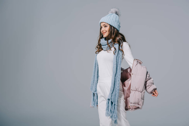 beautiful happy girl posing in coat, knitted hat and scarf, isolated on grey - 写真・画像