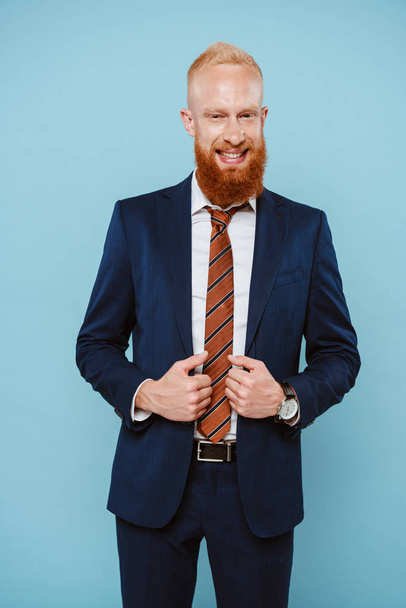 happy bearded businessman in suit, isolated on blue - Foto, Imagen