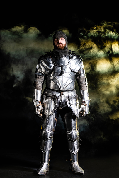 handsome knight in armor looking at camera on black background - Photo, Image