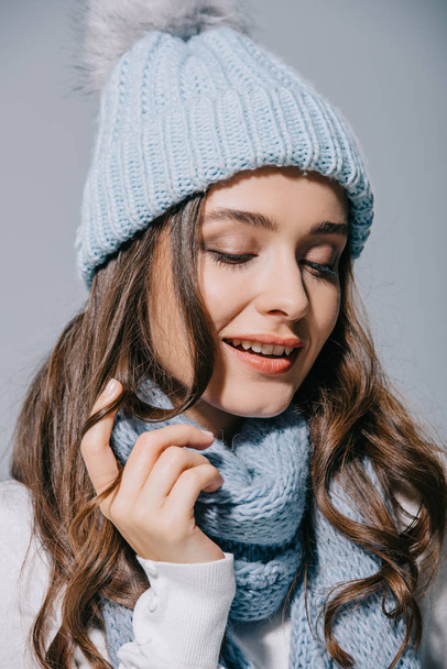 beautiful happy woman posing in blue knitted hat and scarf, isolated on grey - Fotografie, Obrázek
