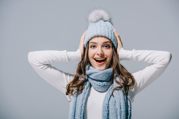 excited girl posing in blue knitted hat and scarf, isolated on grey - 写真・画像