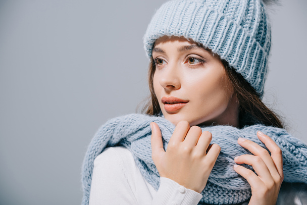 beautiful tender girl posing in blue knitted hat and scarf, isolated on grey - Fotó, kép