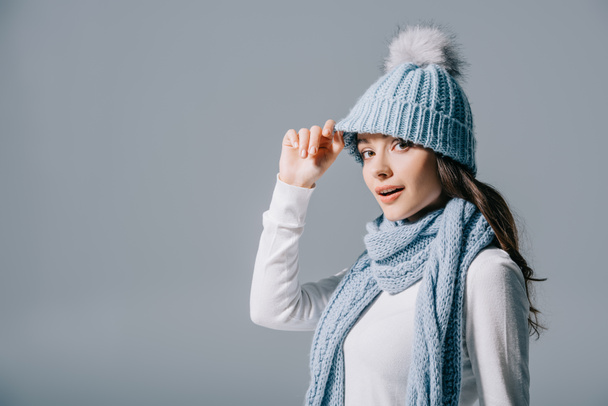 beautiful smiling girl posing in knitted hat and scarf, isolated on grey - Foto, imagen