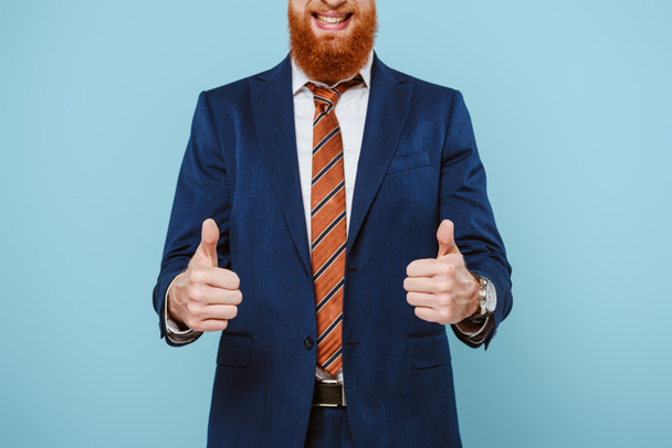 cropped view of smiling businessman in suit showing thumbs up, isolated on blue - Photo, image
