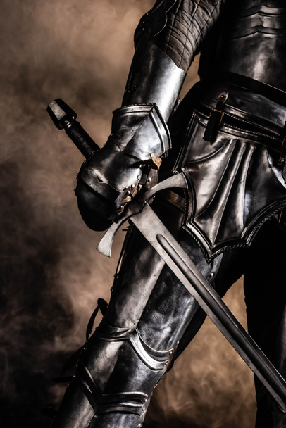 levágott kilátás lovag páncélban tartja kard fekete háttér - Fotó, kép