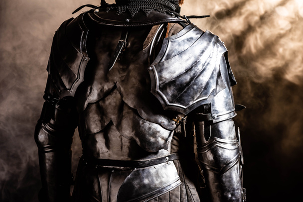 cropped view of knight in armor on black background - 写真・画像