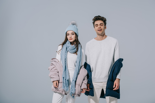 modisches junges Paar posiert im Winteroutfit, isoliert auf grau - Foto, Bild