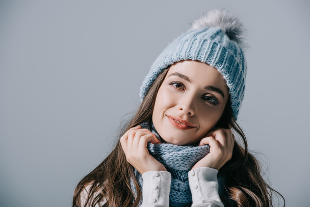 beautiful smiling woman posing in knitted hat and scarf, isolated on grey - Foto, Imagen