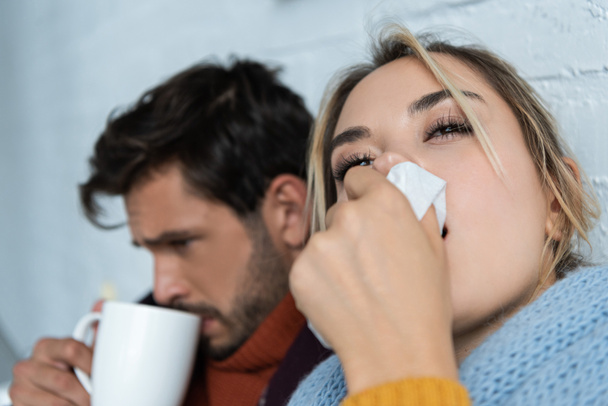 sick man with hot drink and woman with napkin having runny nose - Photo, Image