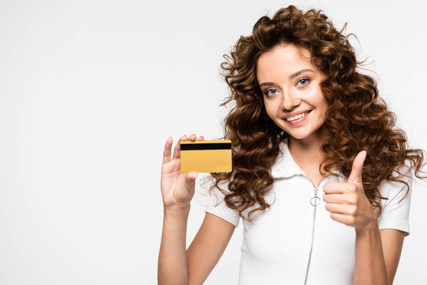 piękny szczęśliwy kręcone dziewczyna pokazując kciuk w górę i karta kredytowa, izolowane na biały - Zdjęcie, obraz