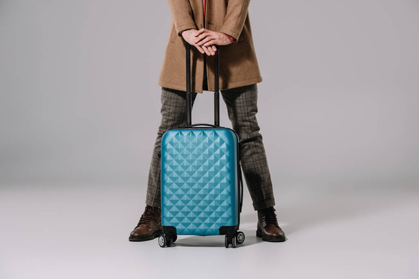 cropped view of man posing with travel bag on grey - Zdjęcie, obraz