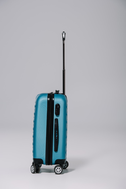mala de plástico azul para viagem em pé sobre cinza
 - Foto, Imagem