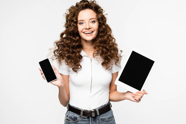 приваблива жінка, що показує смартфон і цифровий планшет з порожніми екранами, ізольована на білому
 - Фото, зображення