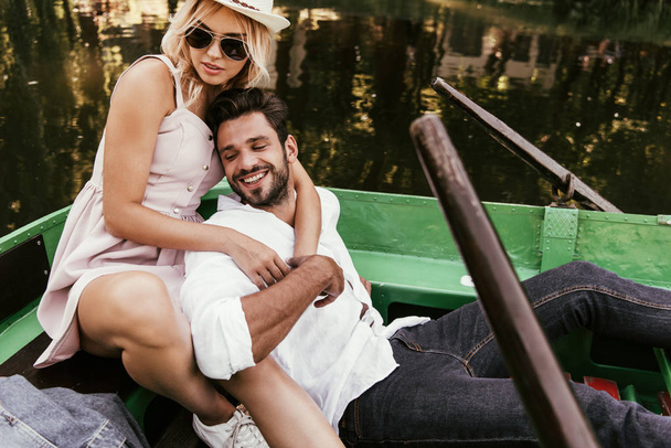 attractive young woman hugging happy boyfriend while sitting in boat - Foto, afbeelding