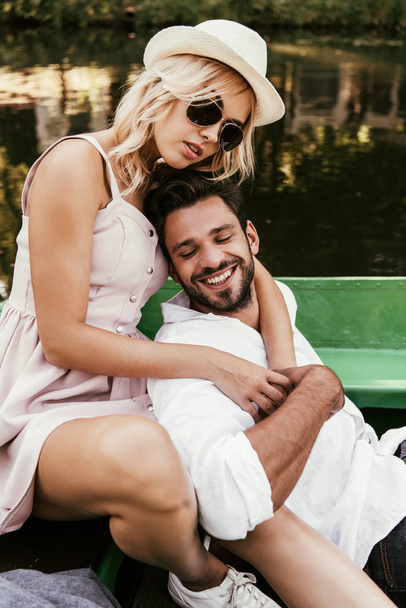 beautiful young woman hugging happy boyfriend while sitting in boat - Foto, imagen