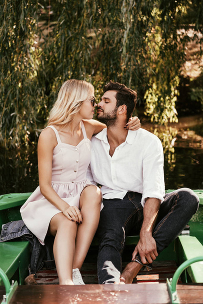 счастливая молодая пара целуется сидя в лодке на озере
 - Фото, изображение