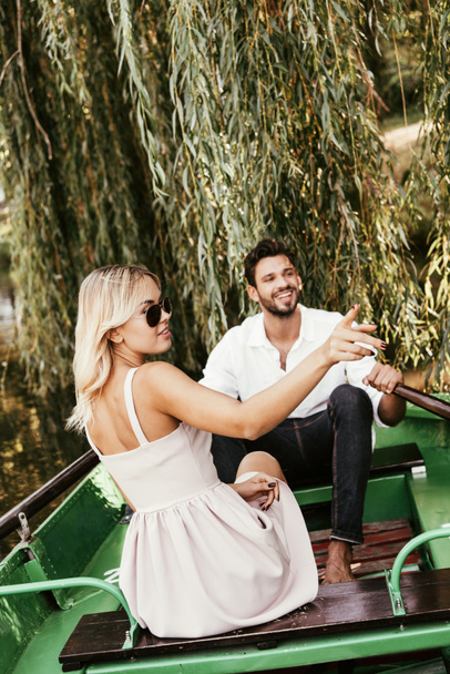 attrayant jeune femme pointant du doigt tout en étant assis dans le bateau près petit ami heureux
 - Photo, image