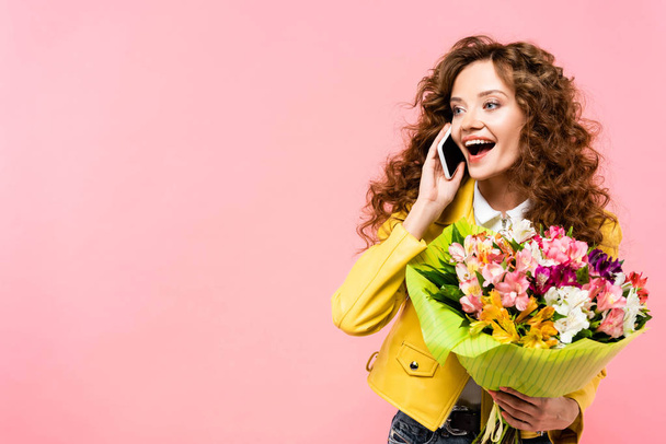 happy curly girl with bouquet of flowers talking on smartphone, isolated on pink - Φωτογραφία, εικόνα