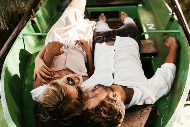 overhead view of young couple looking at each other while lying in boat - Фото, изображение