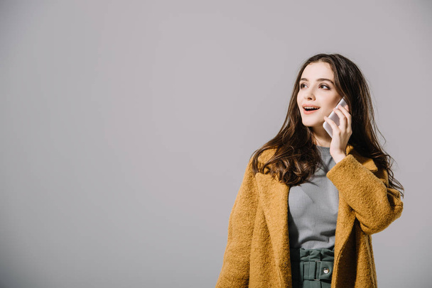 mujer sonriente en abrigo beige hablando en teléfono inteligente, aislado en gris
 - Foto, Imagen