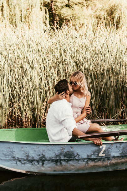 jeune couple embrasser et embrasser en bateau sur la rivière près fourré de carex
 - Photo, image
