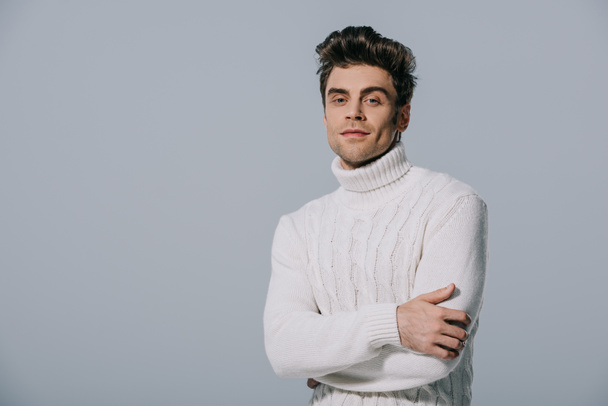 handsome stylish man posing in knitted sweater with crossed arms, isolated on grey - Foto, afbeelding