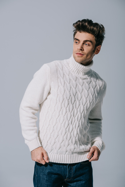 divatos férfi pózol fehér kötött pulóver, elszigetelt szürke - Fotó, kép