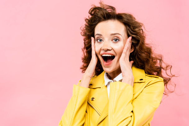 excited curly girl in yellow leather jacket, isolated on pink - Фото, зображення
