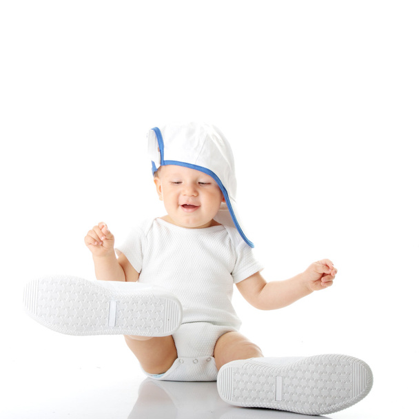 Baby trying on shoes and basebal cap - Фото, изображение