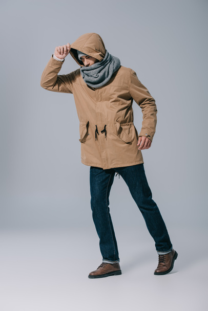fashionable young man posing in hat, scarf and coat on grey - Foto, Imagem