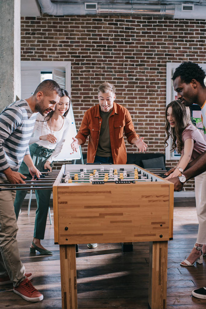 cheerful multicultural businesspeople playing table football in office - Fotografie, Obrázek