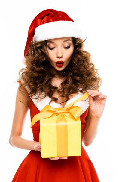 attractive surprised girl in santa costume holding christmas present, isolated on white - Φωτογραφία, εικόνα