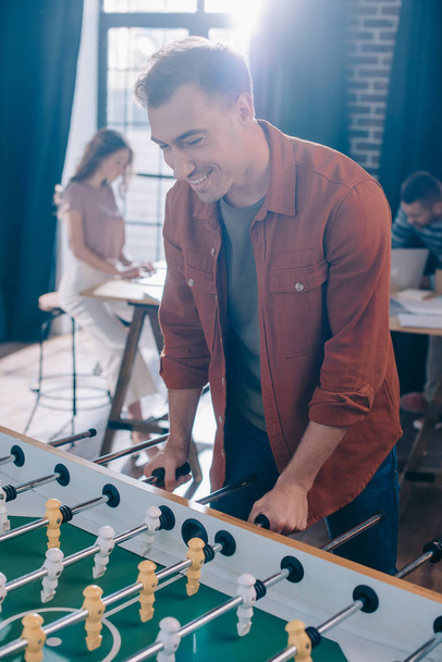 young cheerful businessman playing table football in office - Foto, immagini