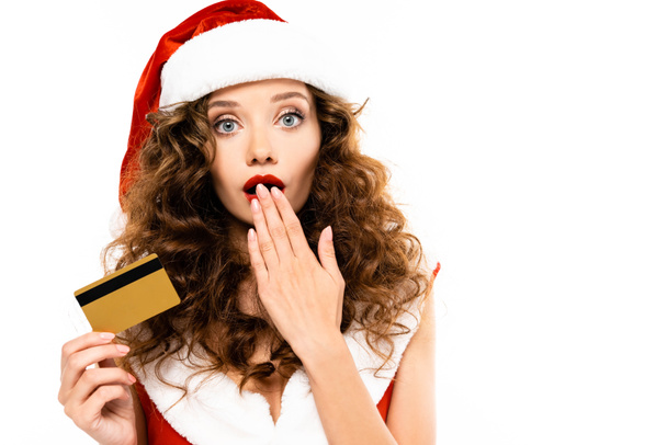 shocked woman in santa costume and hat holding credit card, isolated on white - Foto, Bild