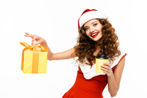 glimlachend meisje in santa kostuum met kerst cadeau en koffie te gaan, geïsoleerd op wit - Foto, afbeelding