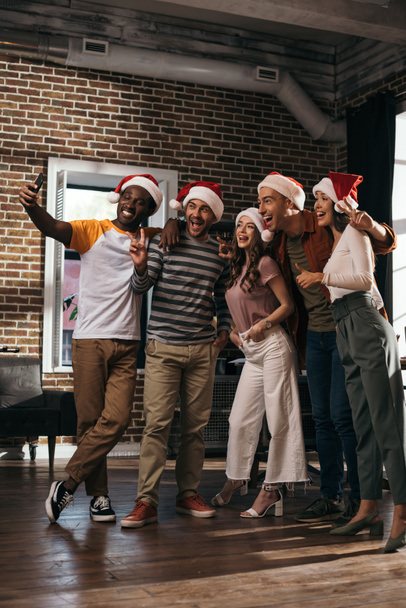 heureux homme d'affaires afro-américain prenant selfie sur smartphone avec des collègues multiculturels joyeux chapeaux Santa
 - Photo, image