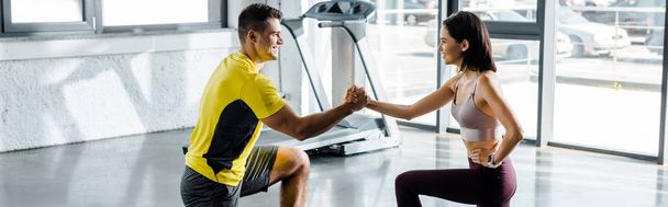 panoramic shot of sportsman and sportswoman doing lunges together in sports center - Foto, imagen