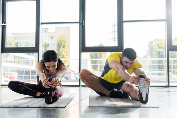 sportsman and sportswoman stretching on fitness mats in sports center - Photo, Image
