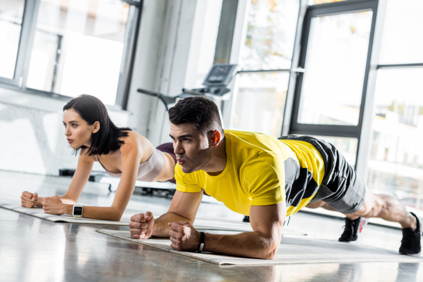 sportsman and sportswoman doing plank on fitness mats in sports center - Foto, afbeelding