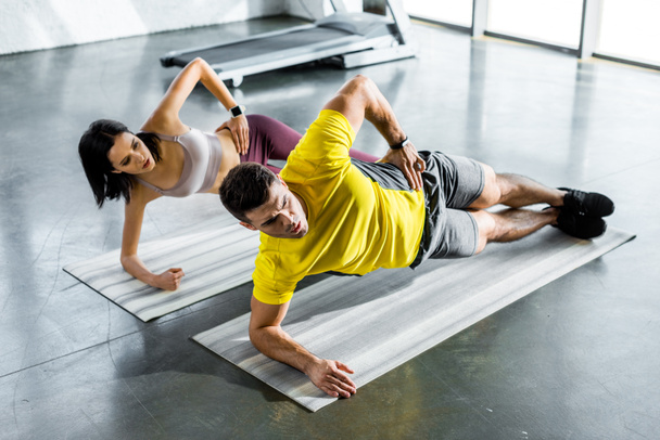 sportsman and sportswoman doing plank on fitness mats in sports center - Zdjęcie, obraz