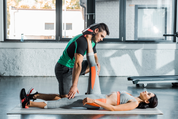 sportswoman stretching and sportsman helping her in sports center - Valokuva, kuva