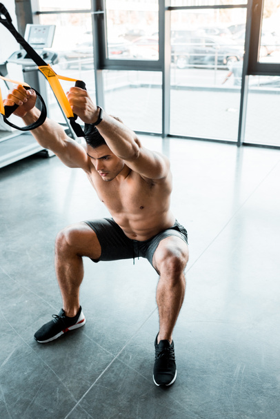 handsome sportsman working out on suspension trainer in sports center  - Photo, Image