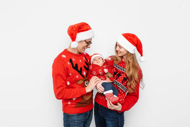 Happy family in Santa hats, mom dad and little baby celebrate Christmas - Photo, Image