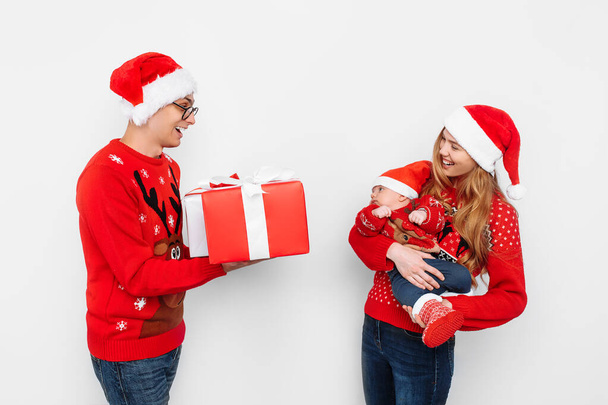 Happy family, dad mom and little baby, celebrate Christmas and give Christmas presents, on a white background - Zdjęcie, obraz