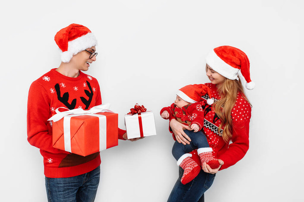 Happy family, dad mom and little baby, celebrate Christmas and give Christmas presents, on a white background - Φωτογραφία, εικόνα