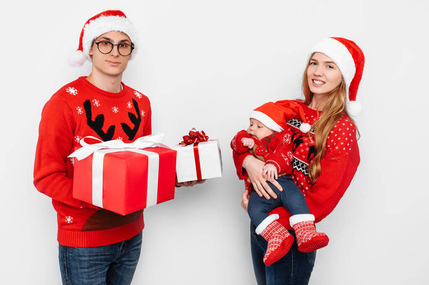 Happy family, mom, dad and little baby with christmas gifts isolated on white background - 写真・画像