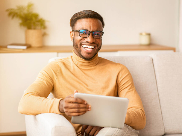 Happy Guy Using Digital Tablet Sitting On Sofa Indoor - Photo, Image
