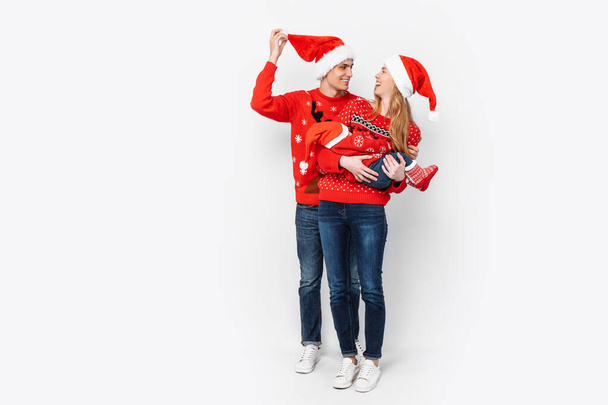 Happy family in Santa hats, mom dad and little baby celebrate Christmas - Φωτογραφία, εικόνα
