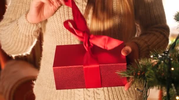 贈り物と一緒に赤い箱を開けて中を見るタウンの女性の4k映像を閉じます。クリスマスや新年のための完璧なショット - 映像、動画